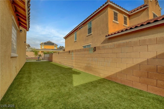 view of side of home featuring a fenced backyard, stucco siding, and a yard