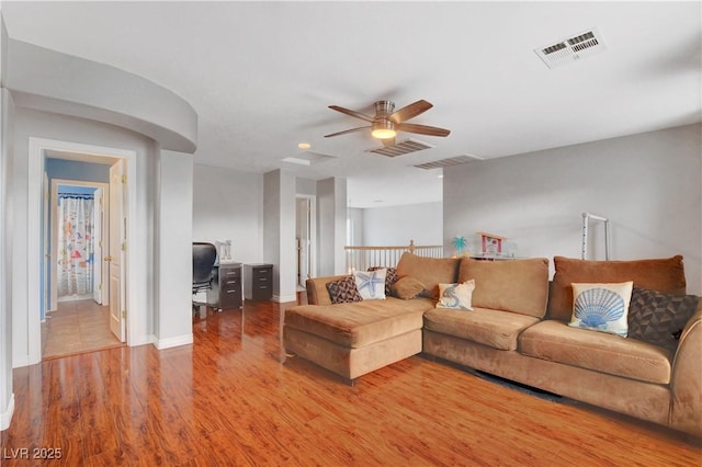 living area featuring a ceiling fan, baseboards, visible vents, and wood finished floors