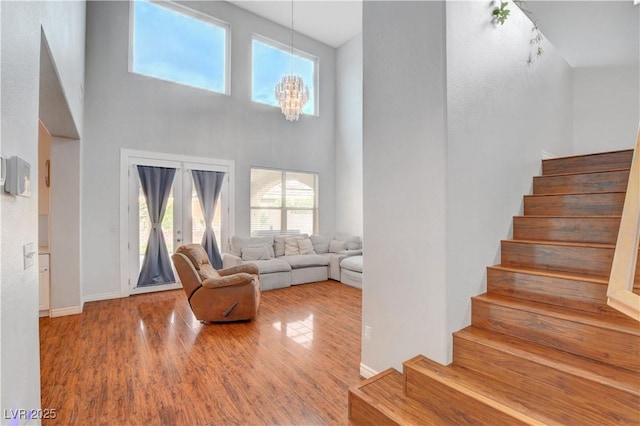 living room featuring plenty of natural light, a high ceiling, stairs, and wood finished floors