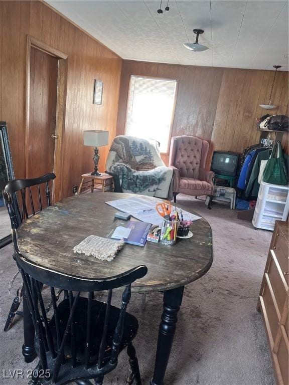 dining space featuring carpet floors and wood walls