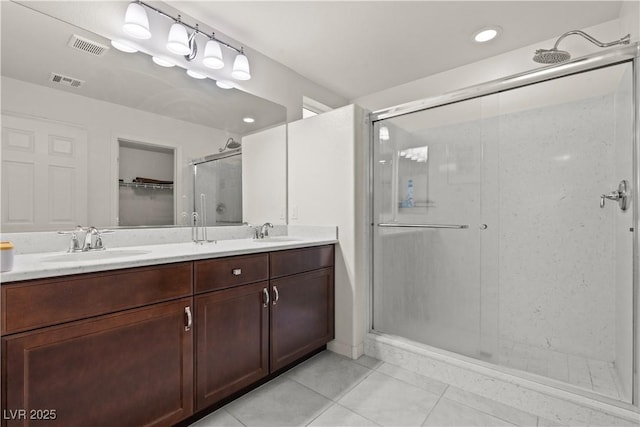 bathroom with double vanity, a sink, tile patterned flooring, and a stall shower