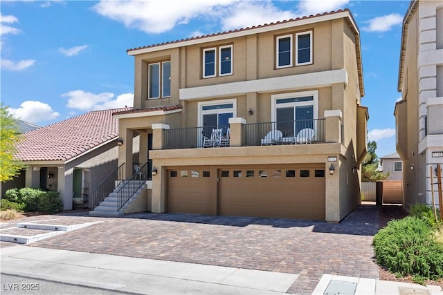 view of property with decorative driveway, a garage, stucco siding, and fence