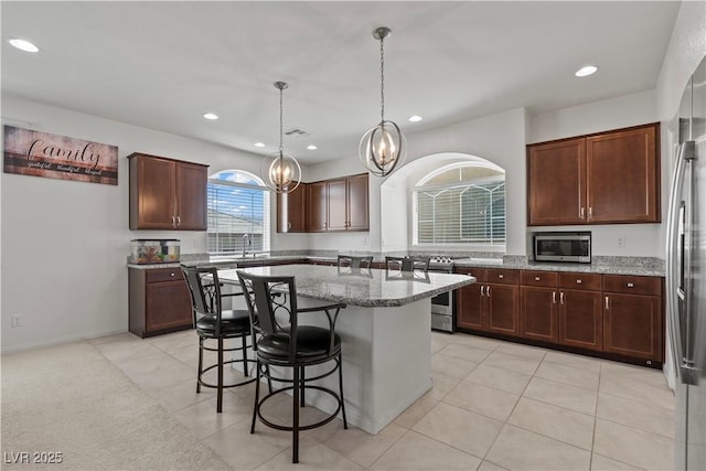 kitchen featuring a kitchen island, light stone counters, a chandelier, stainless steel appliances, and recessed lighting