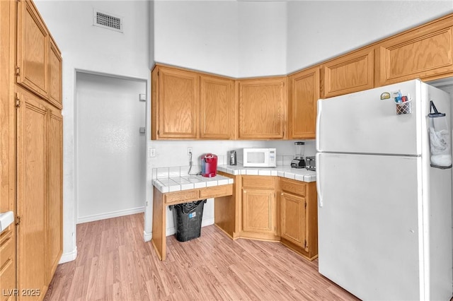 2753 Trickling Brook Ct, Las Vegas, NV 89156 - kitchen with white appliances, tile counters, light wood finished floors, and baseboards