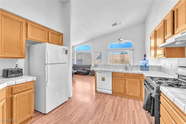 2753 Trickling Brook Ct, Las Vegas, NV 89156 - kitchen with white appliances, under cabinet range hood, light wood finished floors, tile countertops, and high vaulted ceiling