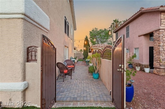 3950 Candleglow Ct, Las Vegas, NV 89147 - property exterior at dusk featuring a gate, stucco siding, a tile roof, and fence