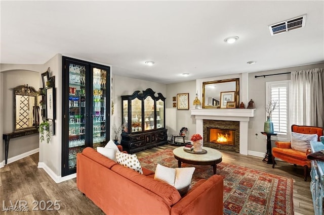 3950 Candleglow Ct, Las Vegas, NV 89147 - living room featuring visible vents, baseboards, wood finished floors, and a warm lit fireplace