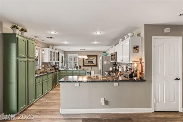 3950 Candleglow Ct, Las Vegas, NV 89147 - kitchen with visible vents, a peninsula, a sink, green cabinets, and stainless steel appliances