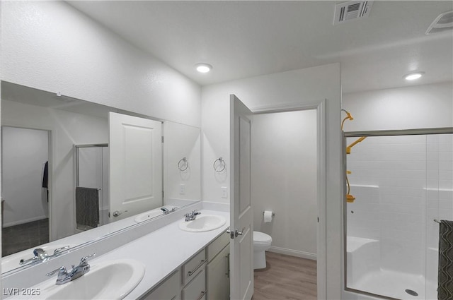 bathroom with toilet, visible vents, a sink, and a stall shower