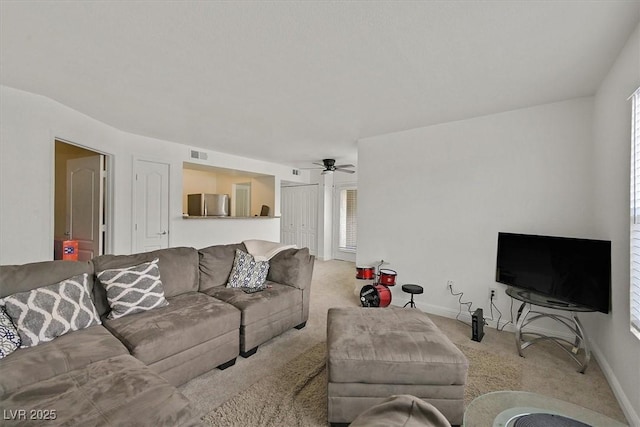 carpeted living area featuring visible vents, plenty of natural light, baseboards, and ceiling fan