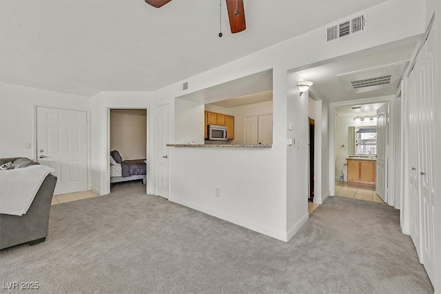 unfurnished living room featuring visible vents, ceiling fan, and light colored carpet