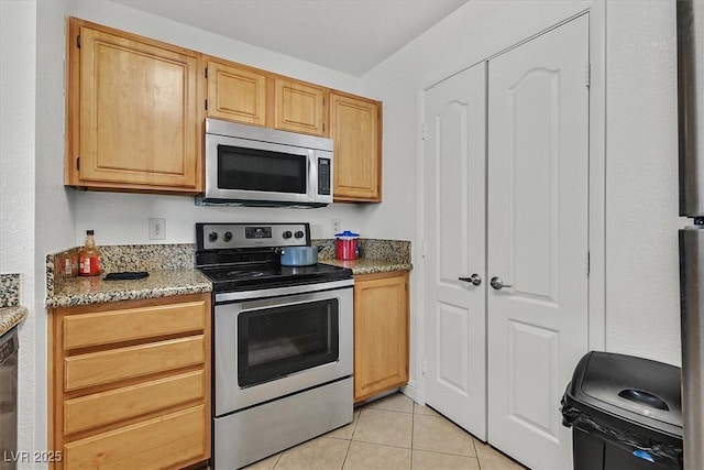 kitchen with stainless steel appliances, light stone counters, and light tile patterned floors