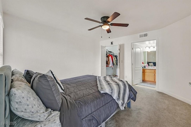 bedroom featuring visible vents, light carpet, baseboards, a walk in closet, and a ceiling fan