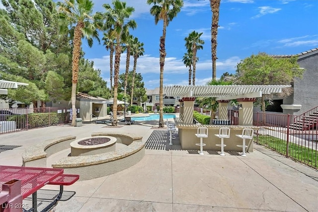 view of patio featuring a community pool, fence, and a fire pit