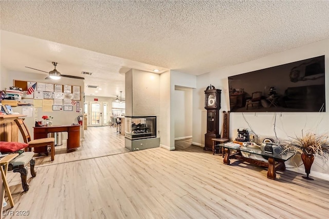 517 7th St, Boulder City, NV 89005 - living room with wood finished floors, a textured ceiling, ceiling fan, baseboards, and a multi sided fireplace