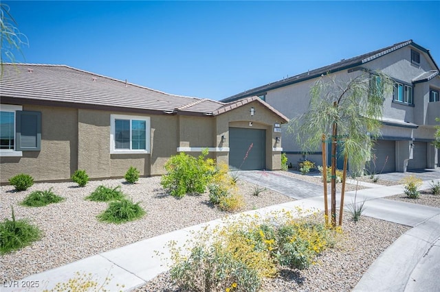 view of front of house featuring a tiled roof, an attached garage, stucco siding, and driveway