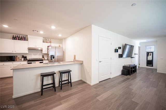 kitchen with visible vents, appliances with stainless steel finishes, dark wood finished floors, a peninsula, and white cabinetry