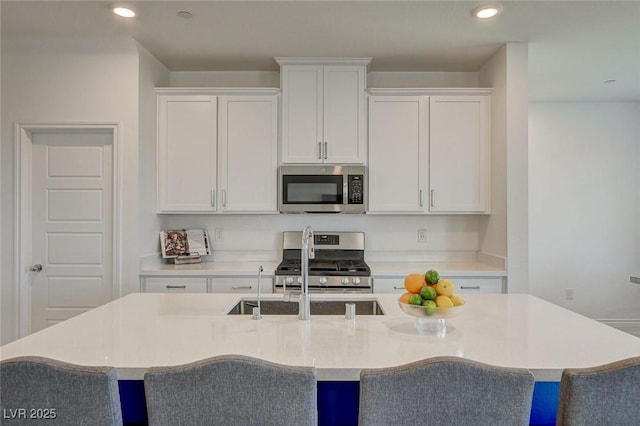 8898 Sasquatch Run Ave, Las Vegas, NV 89166 - kitchen with white cabinetry, appliances with stainless steel finishes, a center island with sink, and a kitchen bar
