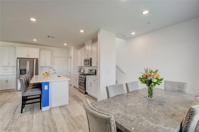 8898 Sasquatch Run Ave, Las Vegas, NV 89166 - kitchen with a breakfast bar area, visible vents, a sink, stainless steel appliances, and white cabinetry