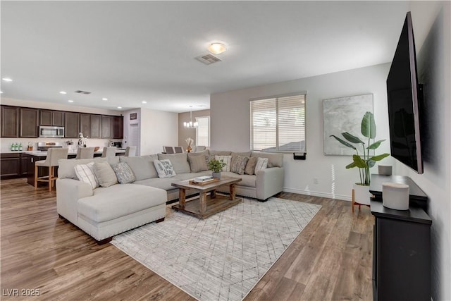 living area with a chandelier, visible vents, recessed lighting, and light wood-type flooring