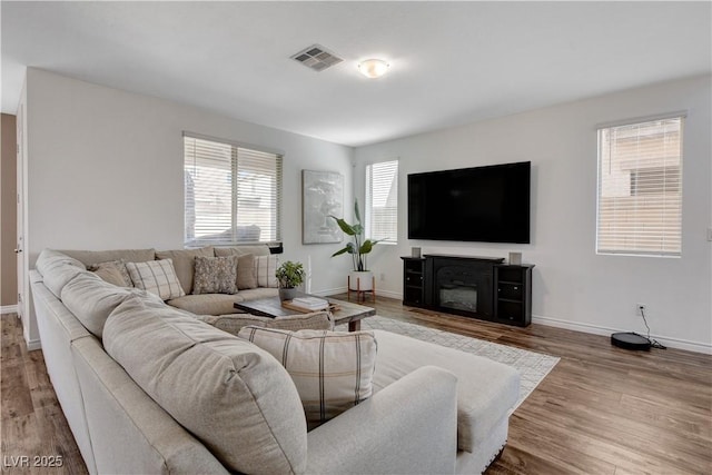 living area with baseboards, visible vents, and wood finished floors
