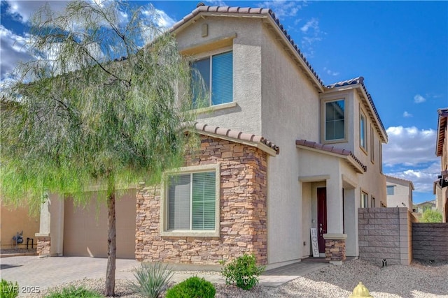 view of front of home featuring fence, stucco siding, a tile roof, and stone siding