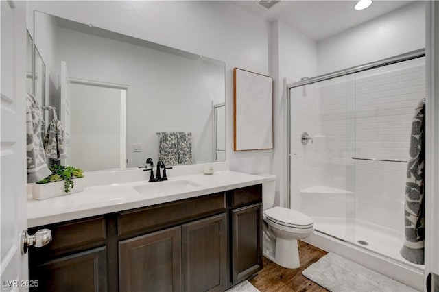 full bathroom featuring vanity, visible vents, wood finished floors, toilet, and a stall shower