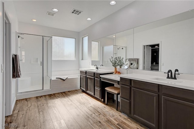 bathroom featuring vanity, visible vents, wood finished floors, a bath, and a shower stall