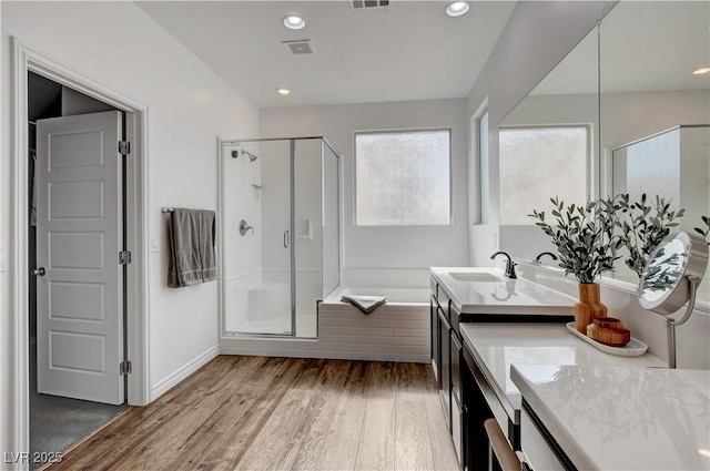 bathroom featuring a bath, visible vents, a stall shower, wood finished floors, and vanity