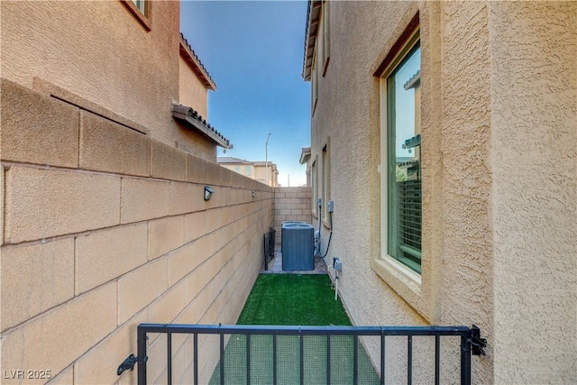 view of property exterior featuring central AC unit, a fenced backyard, and stucco siding