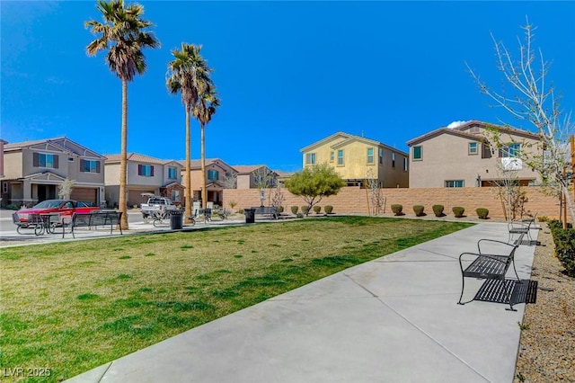 view of community with a lawn, fence, and a residential view