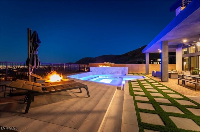 5436 Succulent Rose Dr, Las Vegas, NV 89135 - pool at twilight with an outdoor living space with a fire pit, a fenced backyard, a mountain view, an in ground hot tub, and a patio