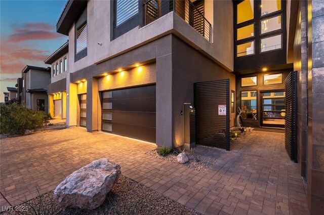 5436 Succulent Rose Dr, Las Vegas, NV 89135 - property exterior at dusk featuring a garage, stucco siding, and decorative driveway