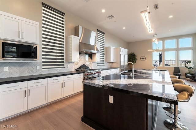 5436 Succulent Rose Dr, Las Vegas, NV 89135 - kitchen with black microwave, a kitchen breakfast bar, wall chimney exhaust hood, range with two ovens, and a sink
