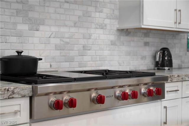 kitchen featuring light countertops, decorative backsplash, white cabinetry, and stainless steel gas stovetop