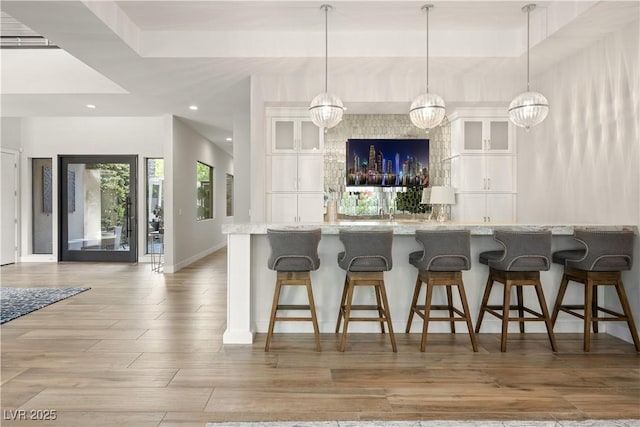 kitchen with a kitchen breakfast bar, baseboards, white cabinets, glass insert cabinets, and recessed lighting