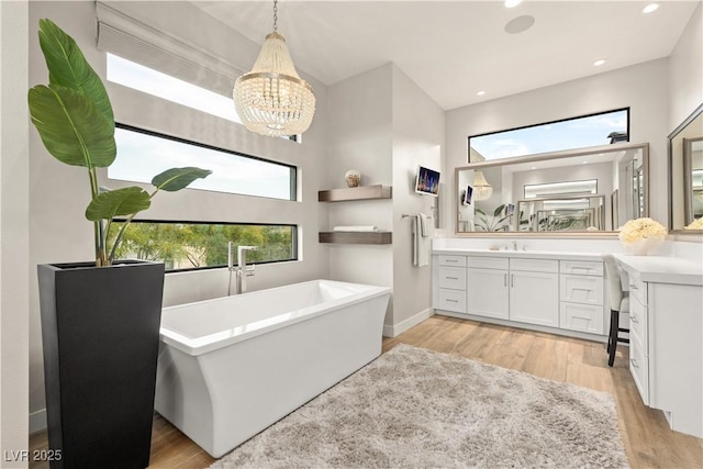 full bathroom featuring vanity, a freestanding tub, wood finished floors, and a notable chandelier