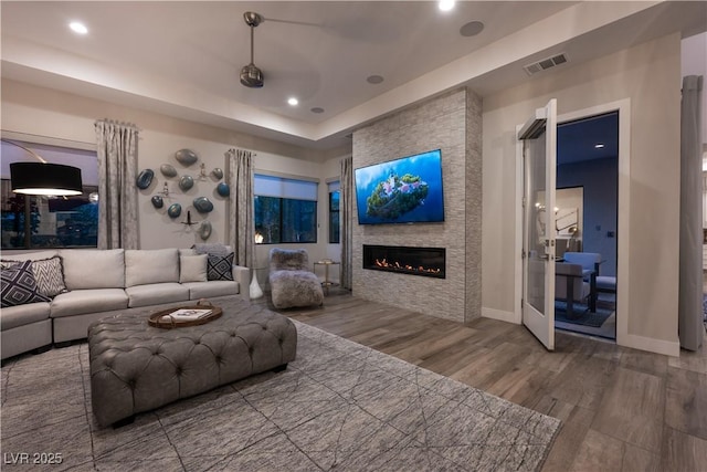 living room with a large fireplace, recessed lighting, baseboards, wood finished floors, and visible vents