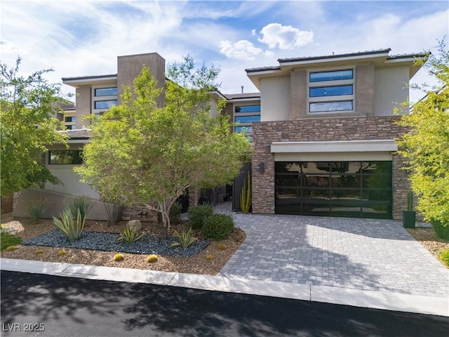 view of front facade featuring stucco siding, decorative driveway, stone siding, and a garage