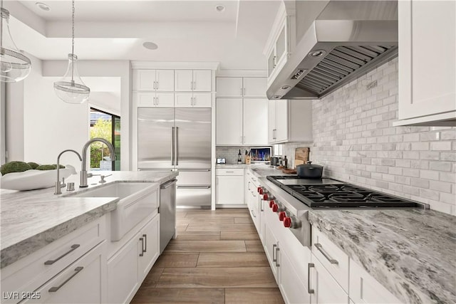 kitchen featuring white cabinets, appliances with stainless steel finishes, a sink, and ventilation hood