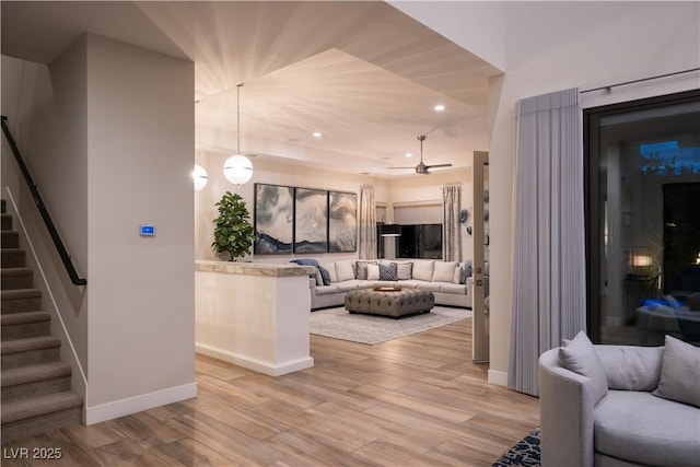 living room featuring stairs, light wood-style floors, baseboards, recessed lighting, and a ceiling fan