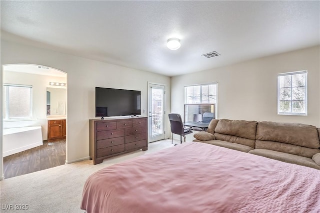 carpeted bedroom with arched walkways, baseboards, access to outside, and visible vents