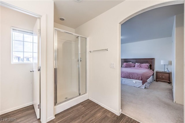 ensuite bathroom with connected bathroom, baseboards, a shower stall, and wood finished floors