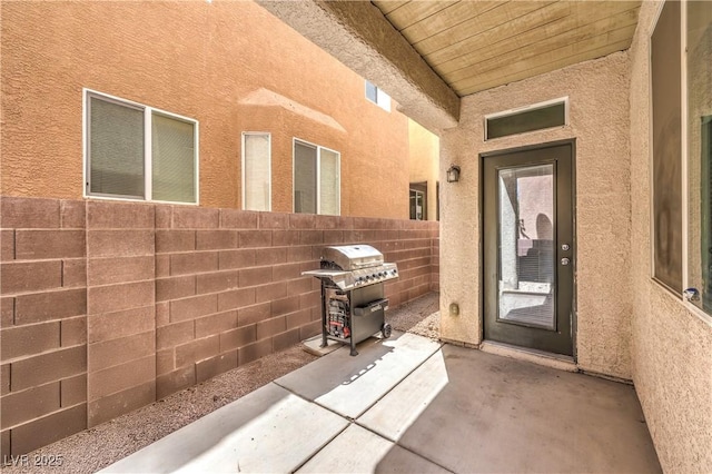 entrance to property featuring a patio, fence, and stucco siding