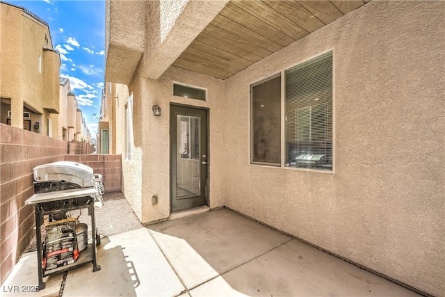entrance to property with a patio area, stucco siding, and fence