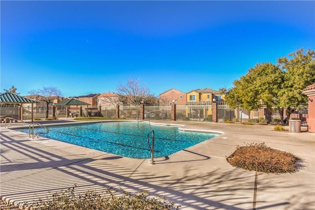 community pool with fence, a gazebo, a patio area, and a residential view
