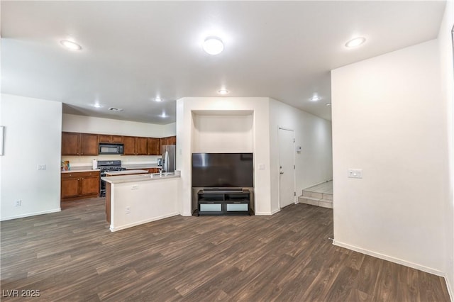 kitchen featuring black microwave, stainless steel fridge, baseboards, dark wood-type flooring, and range with gas cooktop