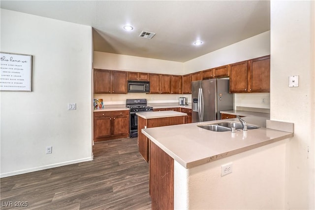 kitchen with visible vents, a kitchen island, dark wood-style floors, a sink, and black appliances