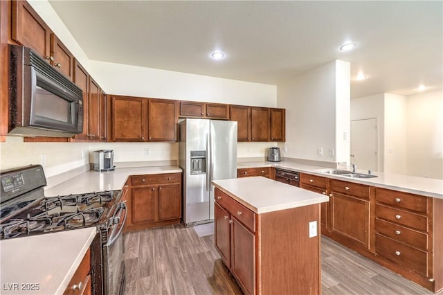 kitchen featuring a peninsula, light wood-type flooring, light countertops, a sink, and black appliances