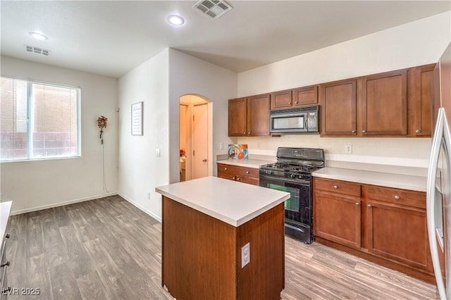 kitchen featuring light countertops, arched walkways, visible vents, and black gas stove
